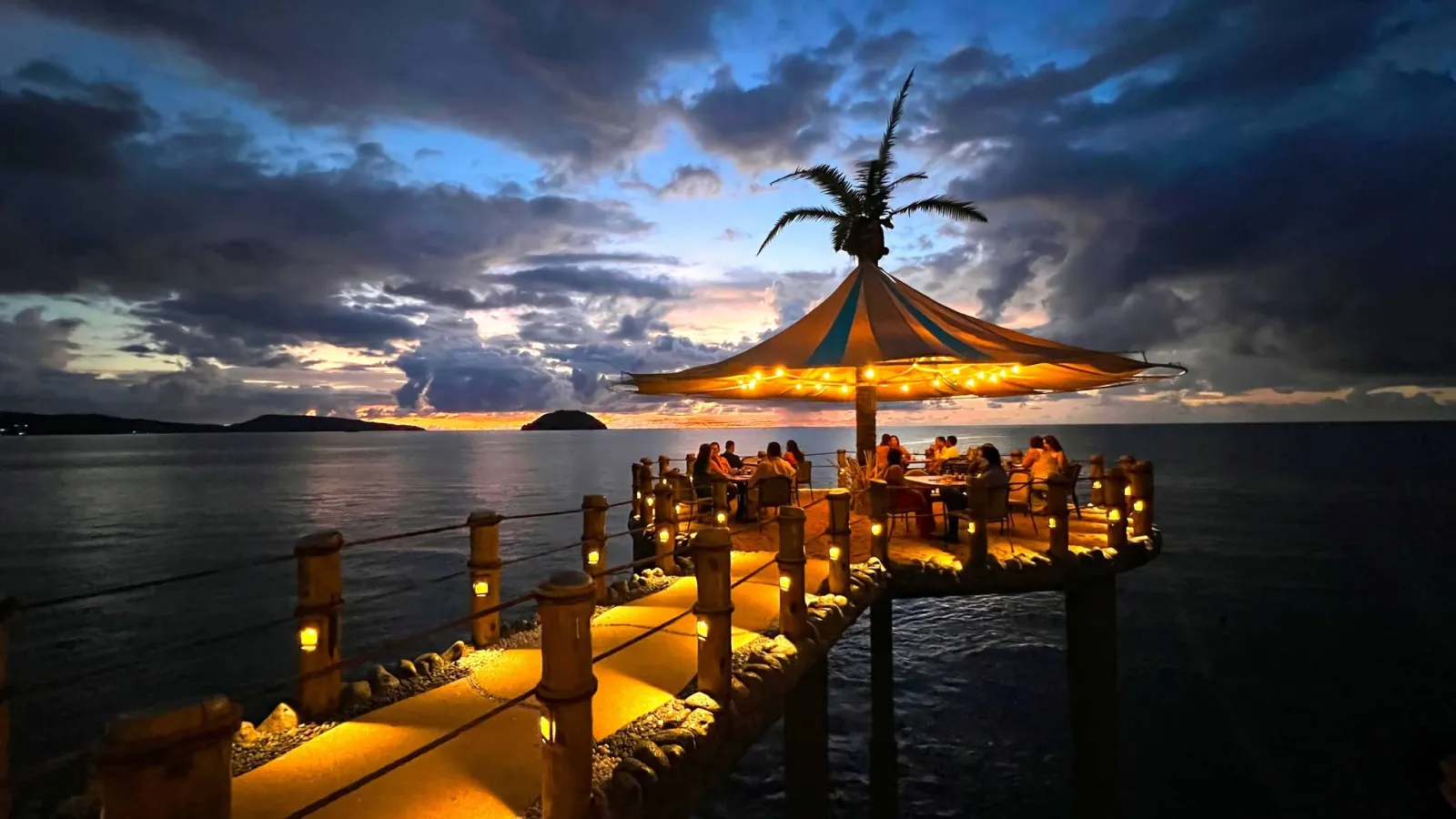 Sunset dinner at La Puesta del Sol's over-water palapa with string lights and ocean views